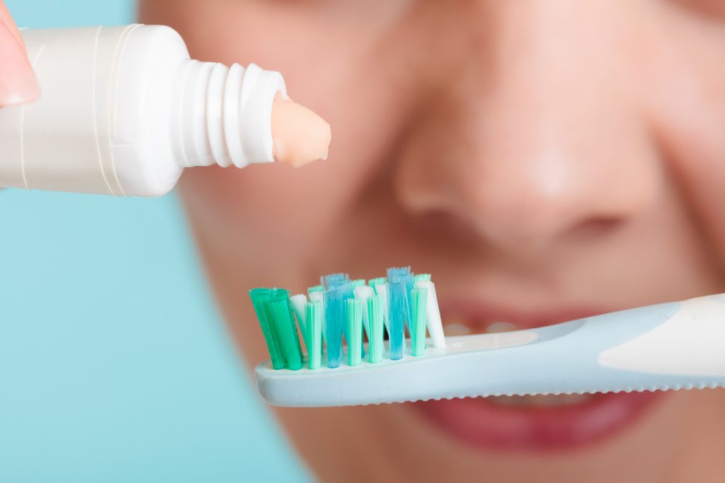 Woman Putting Toothpaste On Toothbrush